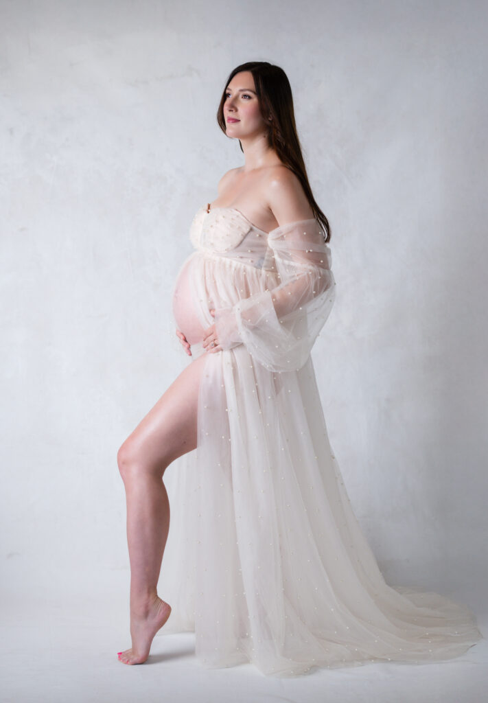 woman posing in maternity gown holding her pregnant belly