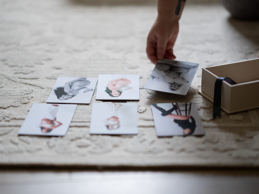 a person laying out print photos from a maternity photo shoot with a keepsake box next to them