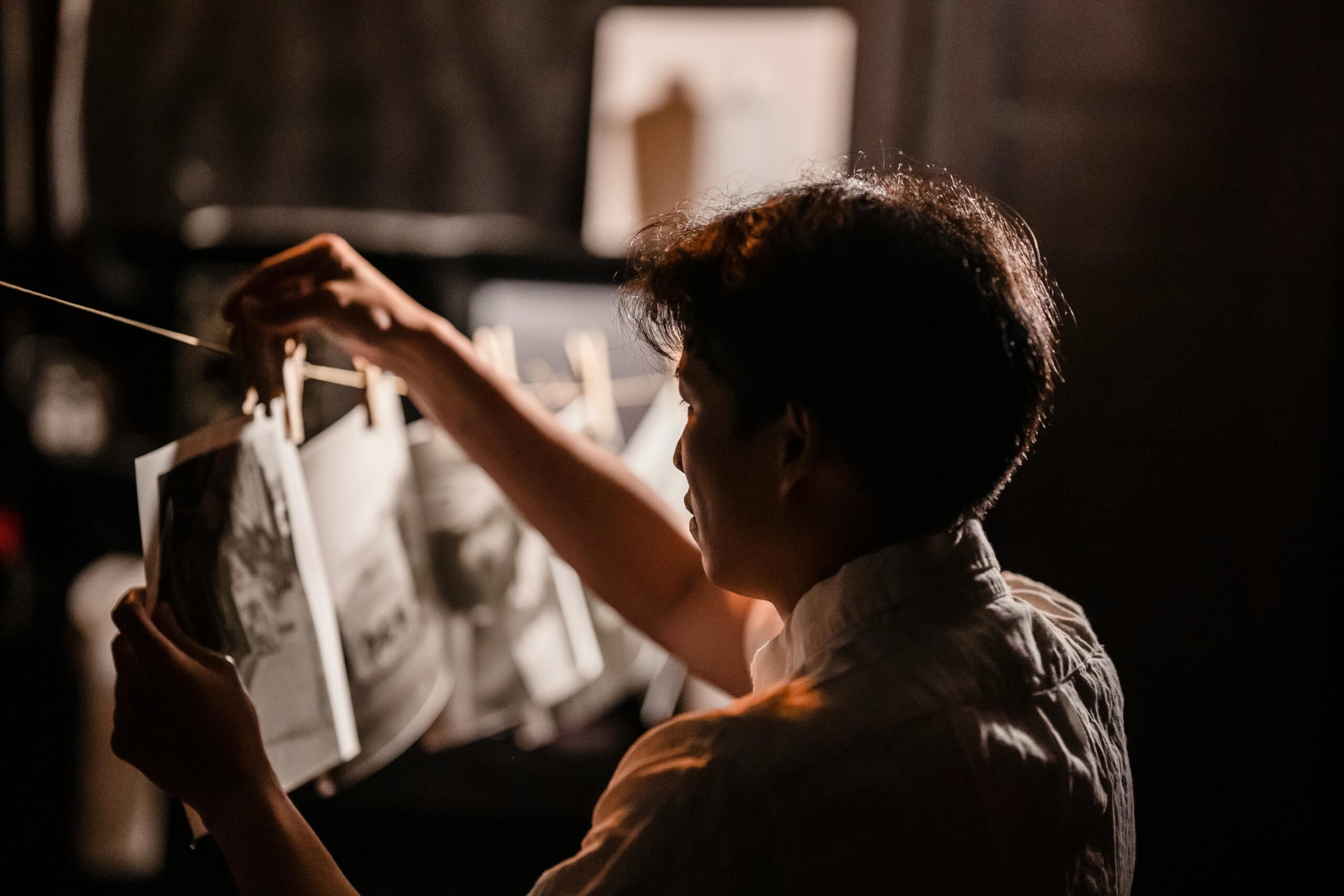 a person hanging up freshly developed film photos on a line