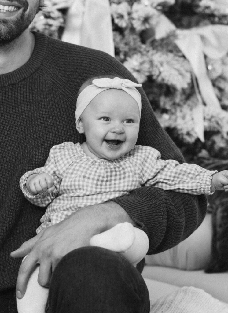 smiling baby being held in dads arms during holiday mini session