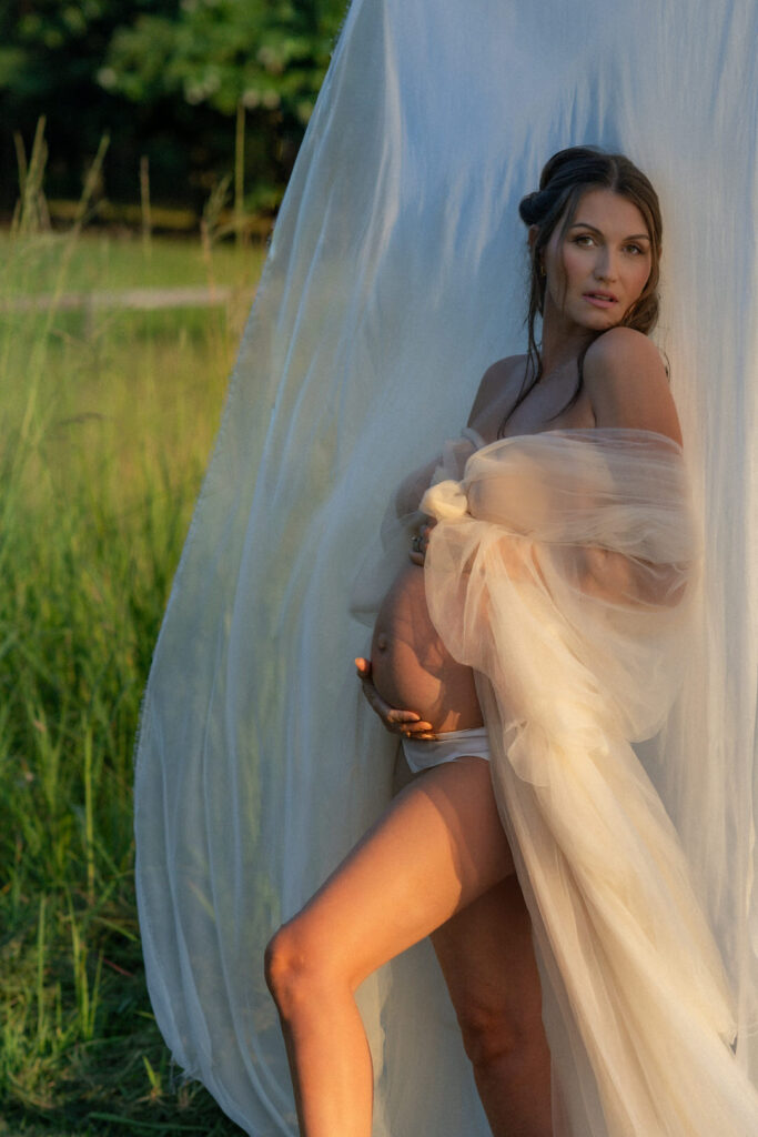 editorial sunset maternity session of mother holding her pregnant belly during golden hour