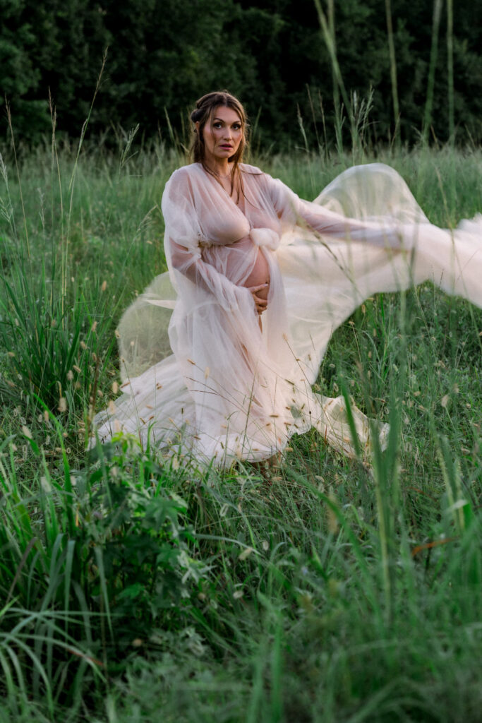 Mother-to-be holding belly with serene sunset backdrop for maternity photos