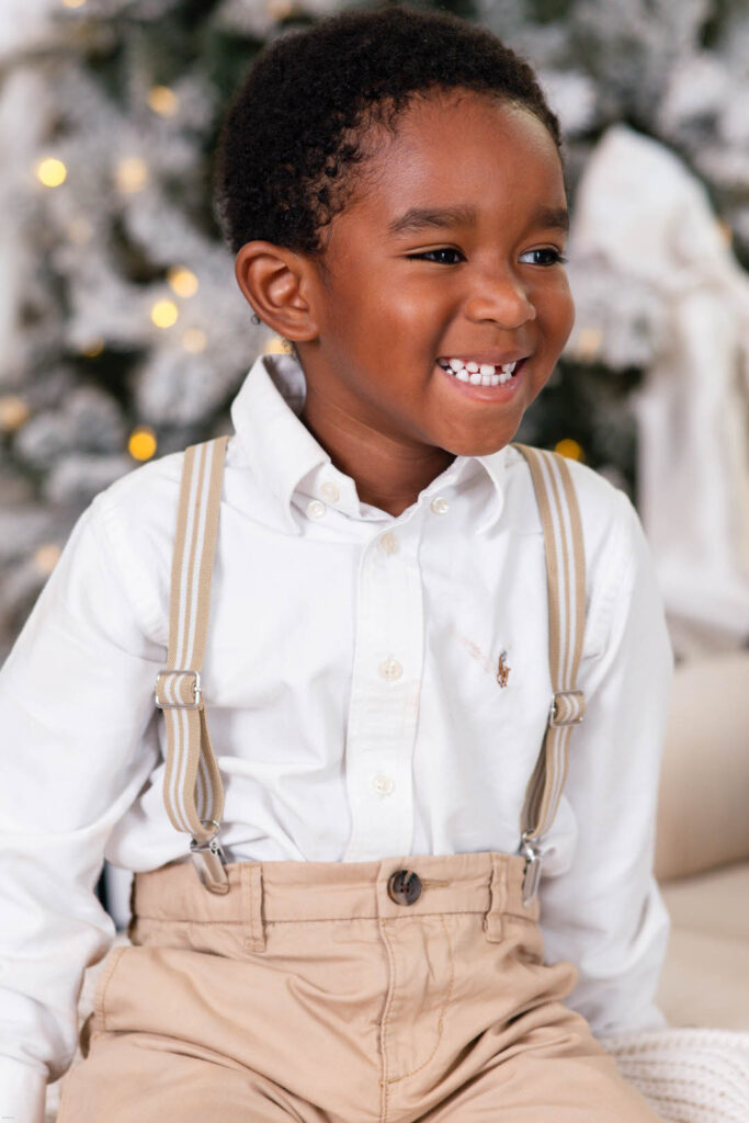 young boy smiling while looking away from camera during holiday mini session