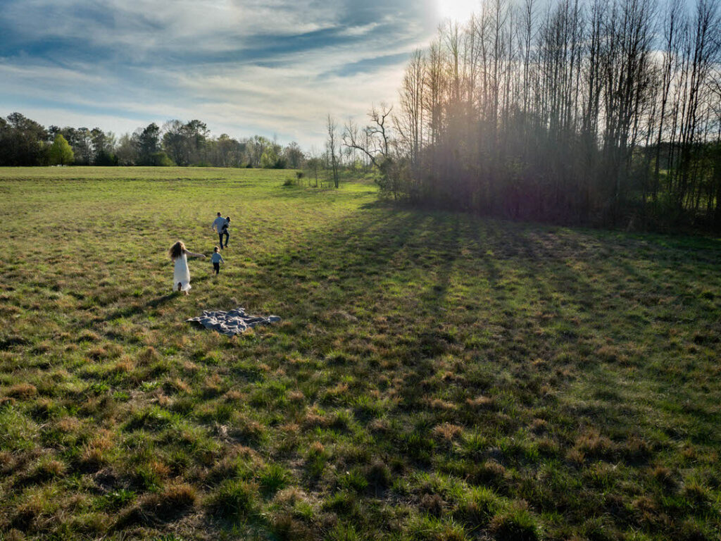 family running in a big field aerial image during golden hour