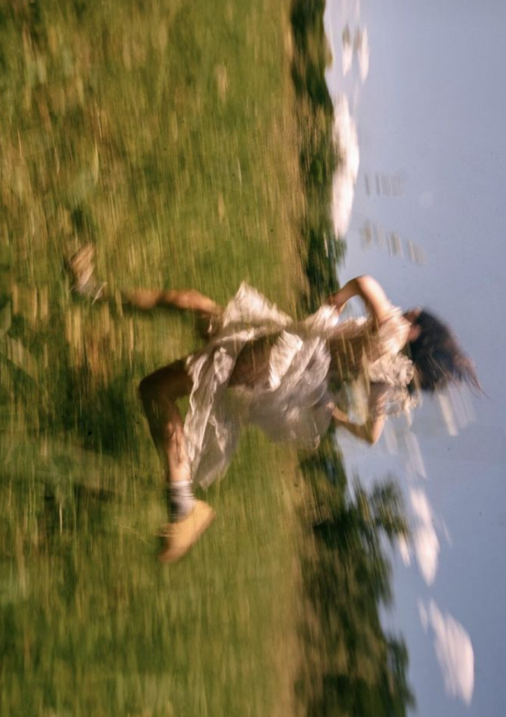woman running in green field in flowing dress