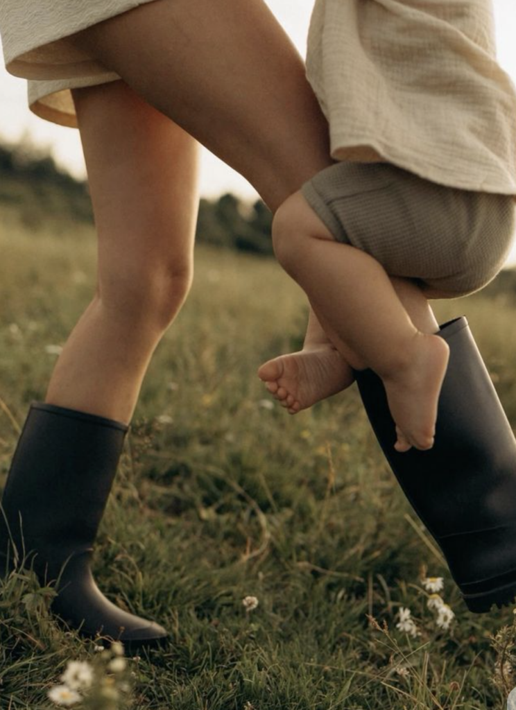 mom walking in field with toddle wrapped around her leg