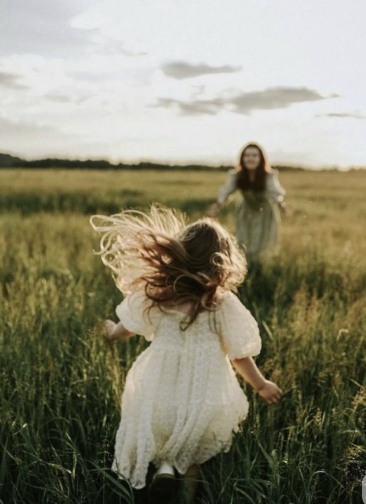 little girl running towards mom in a wide open field