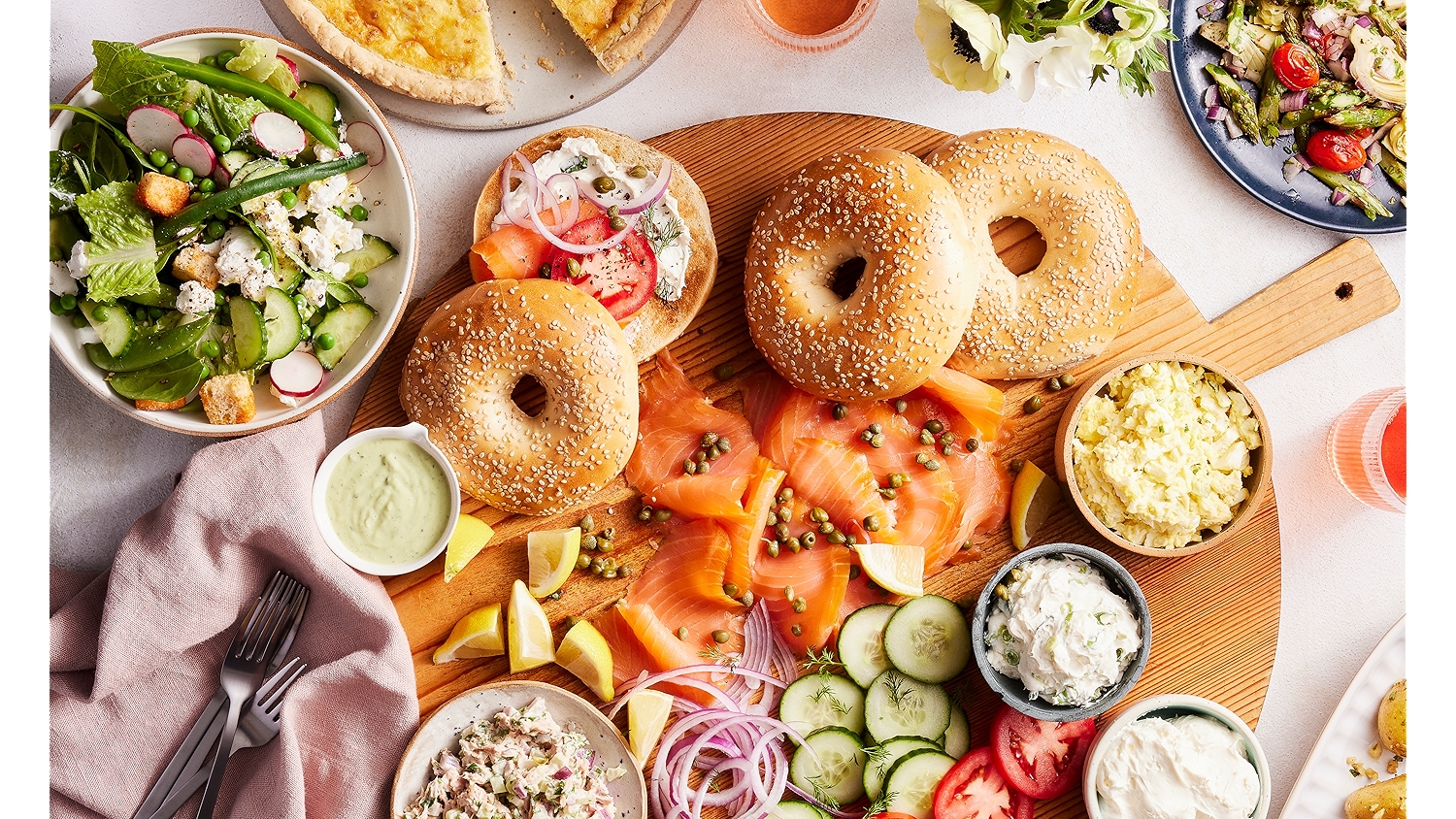 flat lay of a bagel platter with side salads and toppings