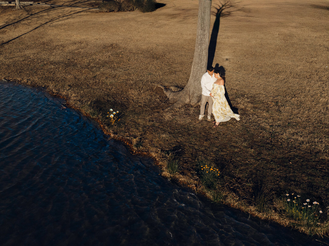 aerial drone shot of a couple lakeside during maternity photoshoot