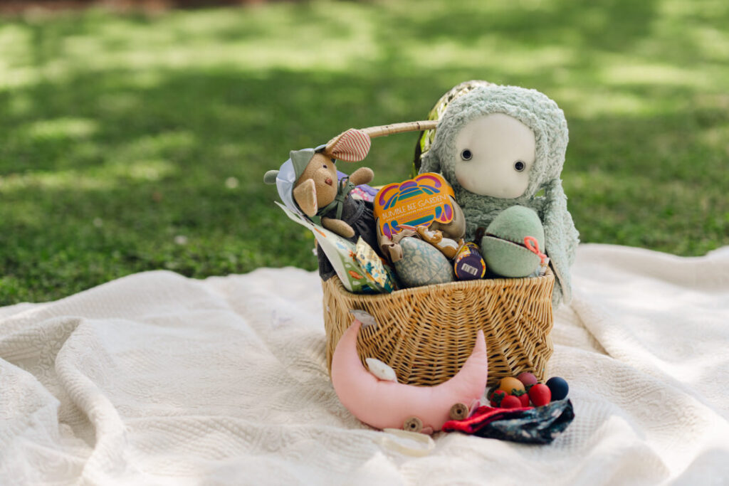 carefully crafted easter basket filled with thrifted and second hand items on a picnic blanket on the grass